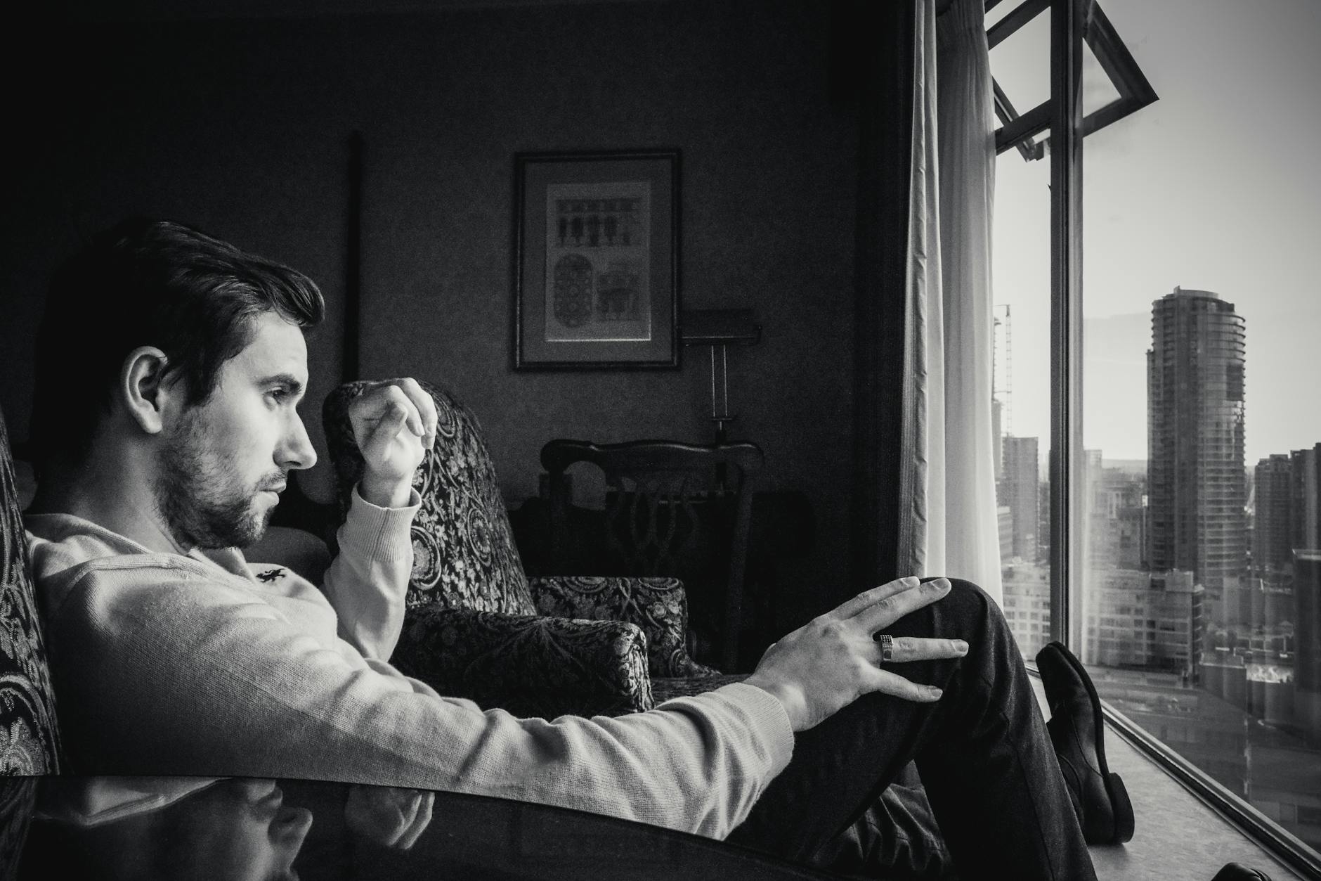 grayscale photo of man looking at window